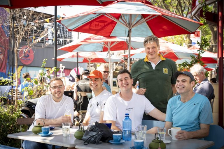 Café: "Friends laughing around a café table under red and white umbrellas in Hazelwood."Workshop17 coming soon